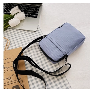 Detail of light blue corduroy crossbody bag texture and adjustable black strap