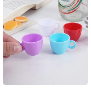 Hand holding a miniature purple toy coffee cup showing its tiny scale for dollhouse decor