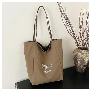 Close-up of khaki tote bag featuring leopard print straps and beyou merci text design