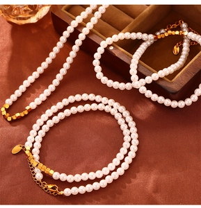 Detailed view of layered faux pearl necklace and bracelet set on brown silk fabric
