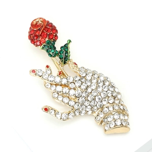Artistic hand holding rose brooch with red crystals and gold alloy base on white background