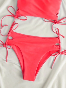 Flat lay of pink bikini set with adjustable side drawstrings and cutout details on fabric