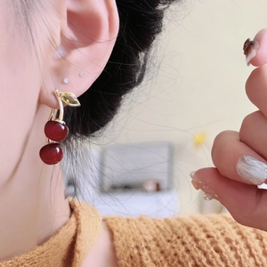 Sweet resin cherry drop earrings with gold leaves on model wearing an orange sweater