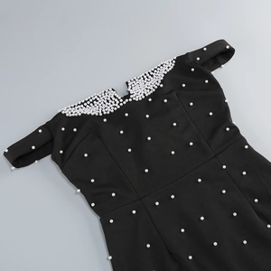 Détail des perles blanches sur l'encolure dénudée d'une robe noire élégante de soirée