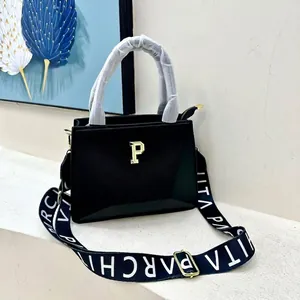 Detail of black pebbled leather tote bag with gold logo and wide branded textile strap