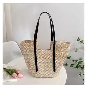 Détail du sac cabas en paille tressé à la main avec texture épaisse et anses en cuir noir