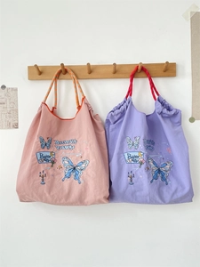 Close-up of pink and purple floral butterfly tote bags with drawstring woven handles