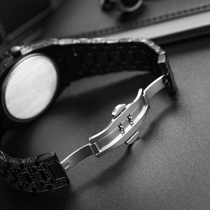 Macro view of iced-out black diamond watch band and silver stainless steel butterfly clasp