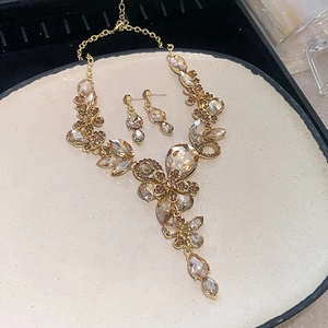Detail view of vintage gold floral jewelry set with champagne crystals on a textured tray