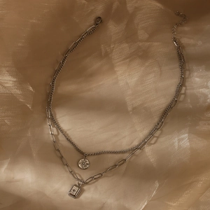 Silver double layer necklace with North Star round charm and square pendant on silk background