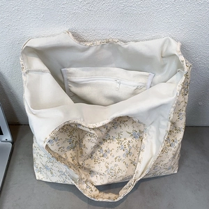 Detail view of the floral canvas tote bag featuring an open inner pocket and a zipper pocket