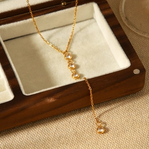 Détail d'un collier en Y plaqué or 18 carats avec zircons dans un écrin en bois