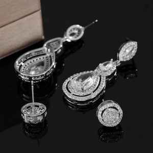 Detailed view of silver teardrop earrings and studs with sparkling zircon on black mirror
