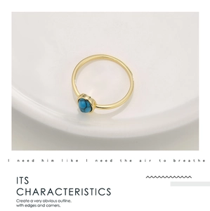 Detailed shot of bohemian gold ring featuring an oval turquoise stone on ceramic dish