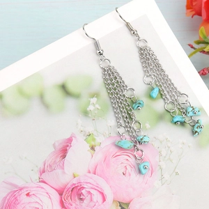 Detailed close-up of long silver tassel earrings with turquoise stone beads on card