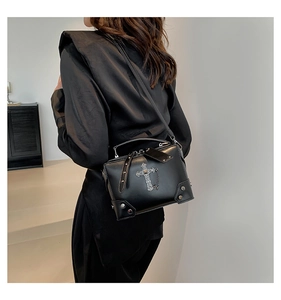 Detail of black gothic crossbody bag featuring silver cross relief and chain decoration