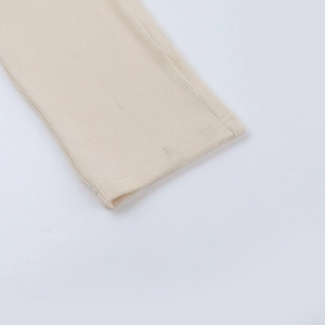 Dettaglio della trama a costine in maglia beige e cuciture di una tuta aderente alla moda
