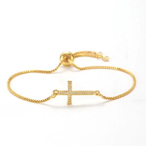 Close-up of golden cross bracelet with cubic zirconia inlay and adjustable slider clasp