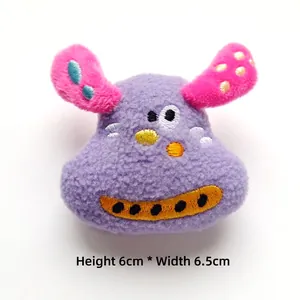 Detail of purple plush dog doll with pink ears and embroidery measuring 6cm by 6.5cm