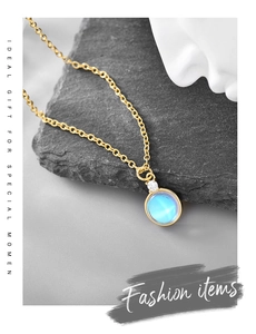 Detailed macro view of gold necklace with blue moonstone on gray rock background