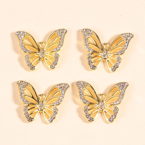 Macro shot of four golden butterfly charms with hollow wings and sparkling crystals