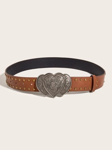 Detail of a brown leather belt with golden rivets and ornate silver heart-shaped buckle
