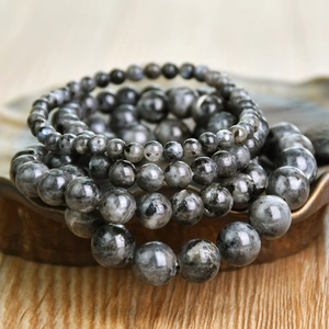 Mehrlagige graue Mondstein-Armbänder in verschiedenen Größen auf einem Holztablett