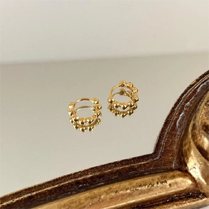 Polished gold beaded hoop earrings in 925 sterling silver on a vintage mirror surface