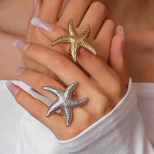Detail of oversized starfish rings in gold and silver finish on model hands