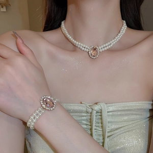 Detailed view of double-layer pearl necklace and bracelet with pink oval gemstone
