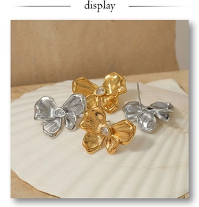 Detail of gold and silver butterfly stud earrings with zircon on a white shell