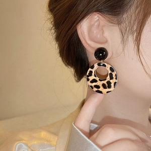 Close-up of leopard print hollow circular drop earrings worn by a model in soft lighting