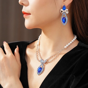 Elegant vintage silver necklace and earring set with blue gem bow pendants on a model
