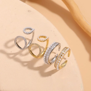 Detailed view of gold and silver plated open rings with pearls and sparkling zircons