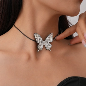 Macro detail of silver butterfly pendant with white rhinestones on black choker