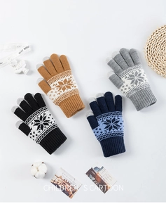 Detailed view of four pairs of knitted winter gloves with snowflake patterns for kids