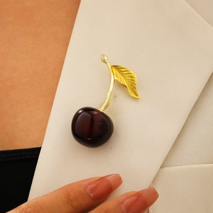 Vue détaillée de la broche cerise avec fruits rouge foncé et feuille en métal doré