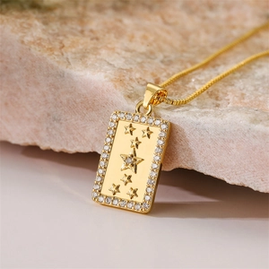 Macro detail of gold rectangle pendant with star relief and sparkling zircon border