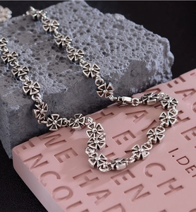 Macro view of vintage silver cross-flower chain necklace with gothic engraved details
