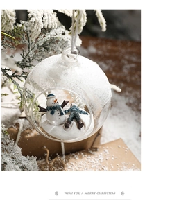 Close-up of clear glass Christmas ball with snowman miniature on snowy tree branch