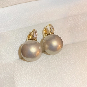 Gros plan de boucles d'oreilles en or en U avec zircons et perles gris champagne