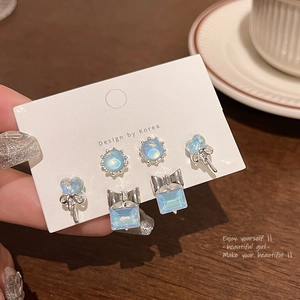 Primer plano de pendientes de plata con ópalos irisados azul claro resplandecientes