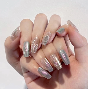 Close-up of coffin-shaped press-on nails with silver cat-eye gel and white wavy lines