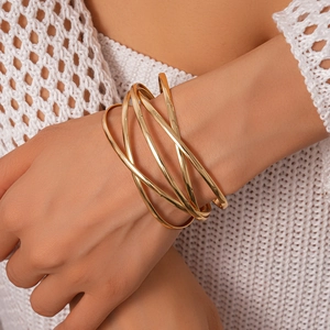 Detailed view of multilayer gold metal bangle with polished geometric crossover design