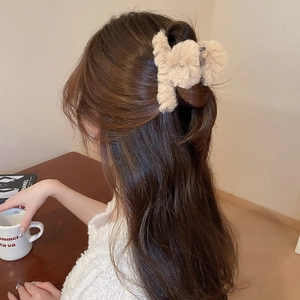 Detailed view of plush beige faux fur hair claw clip styled in a half-up bun hairstyle