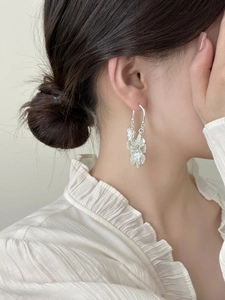 Detail view of silver tassel petal earrings worn by a model in a minimalist style