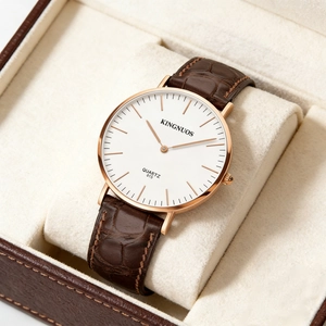 Detail of KINGNUOS quartz watch featuring white dial, rose gold case and brown leather strap