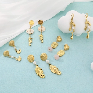 Detail of gold marine earrings set featuring seahorse and pearl elements on silk fabric