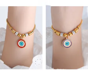 Detail of bohemian gold snake chains with red and lilac evil eye enamel pendants