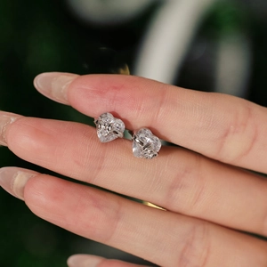 Macro shot of silver S925 heart-cut stud earrings with sparkling clear gemstones